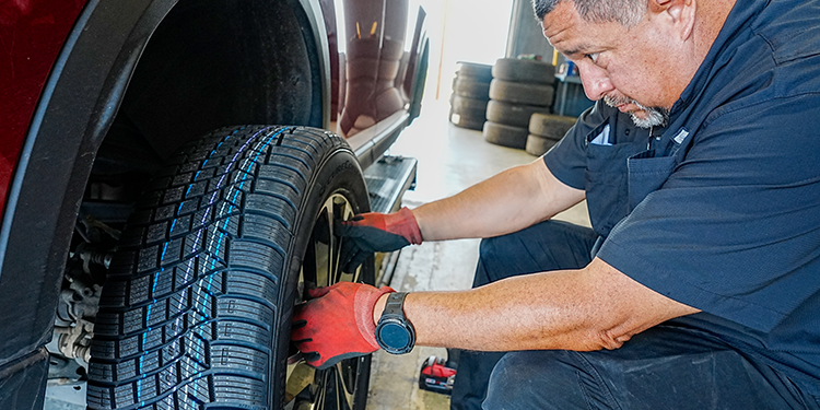 A mechanic installing a new tire on a car in a service garage.