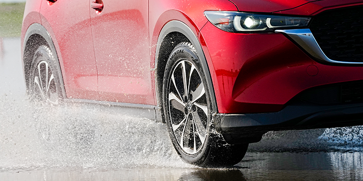 Red car safely cornering on a wet road.