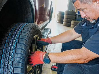 A mechanic installing a new tire on a car in a service garage.