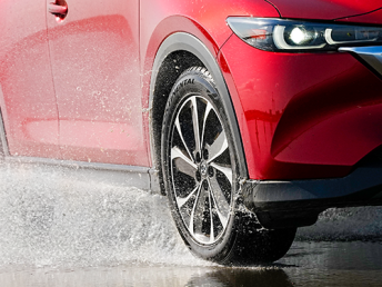 Red car safely cornering on a wet road.